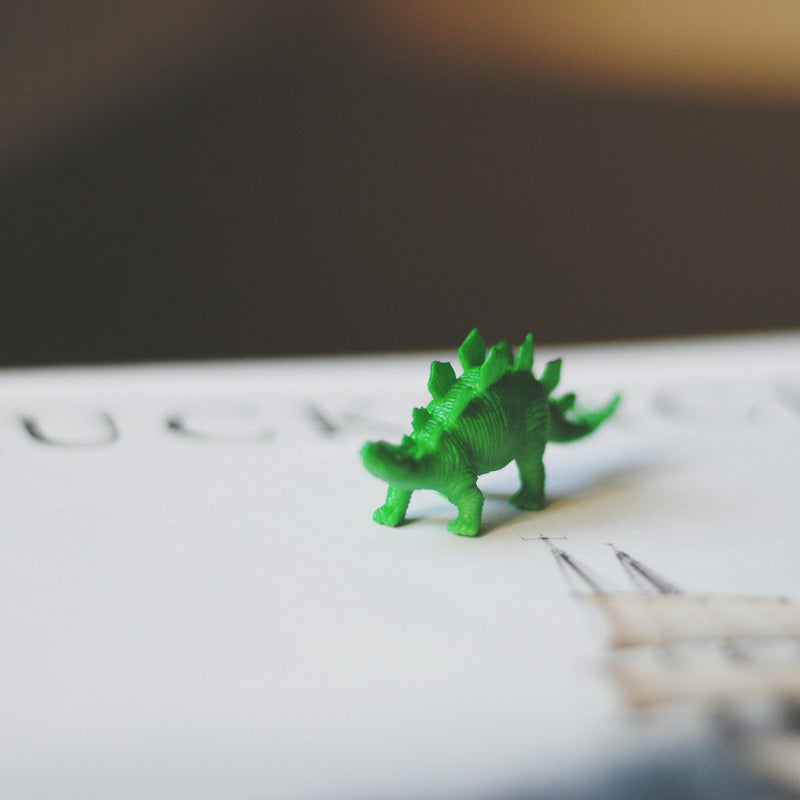 A close-up of a small green toy dinosaur figure
