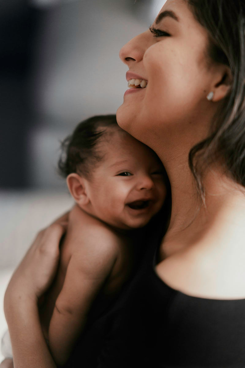 A woman carrying and closely interacting with a smiling baby