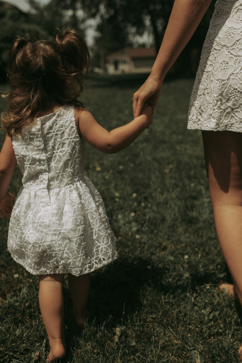 A mother holding the hand of her young daughter