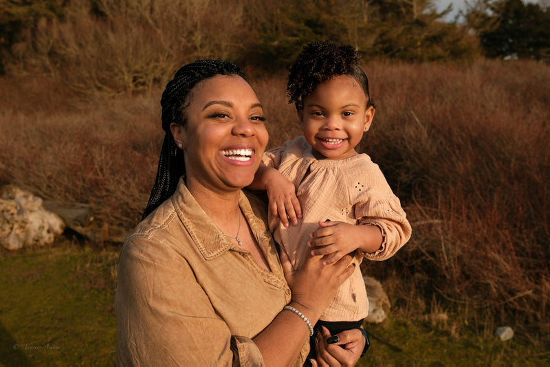 A woman holding a small child closely in her arms outdoors, a warm comforting embrace