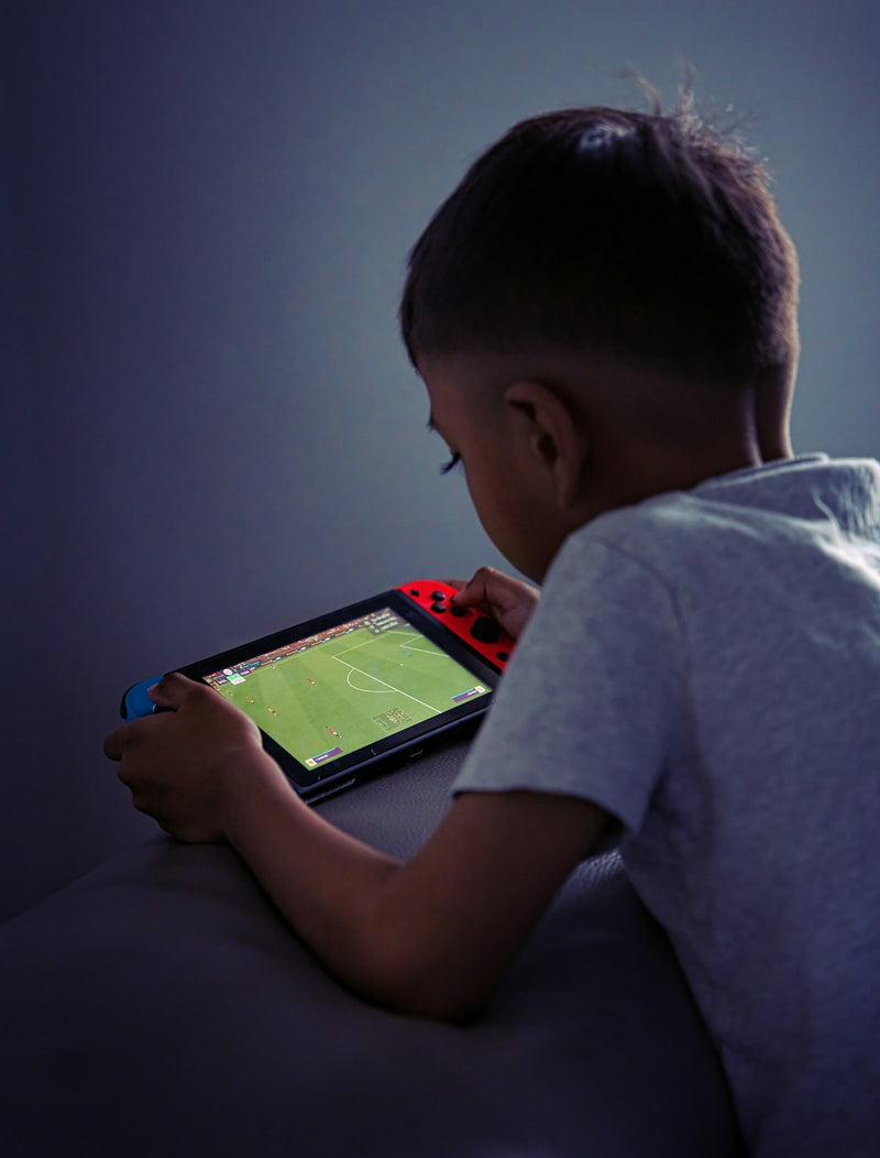 A young boy playing a football video game on a handheld games console.