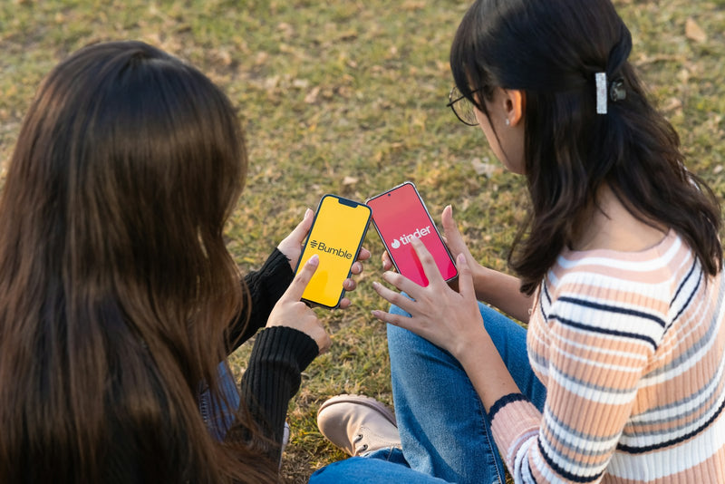 Two young girls sitting on the floor together, closely looking at and pointing at a picture book