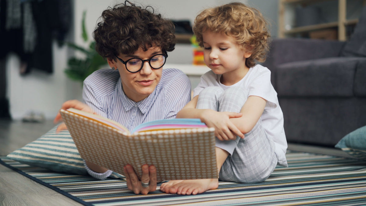 A parent and child reading a picture book together at home