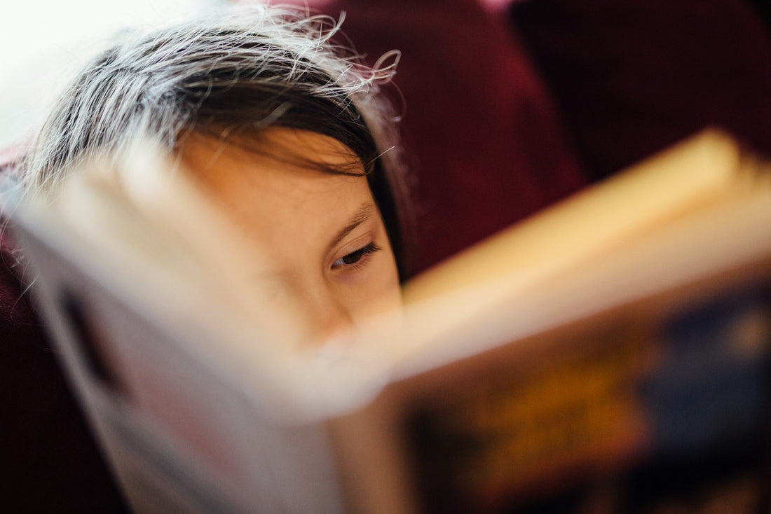 A child absorbed in reading a book on their own