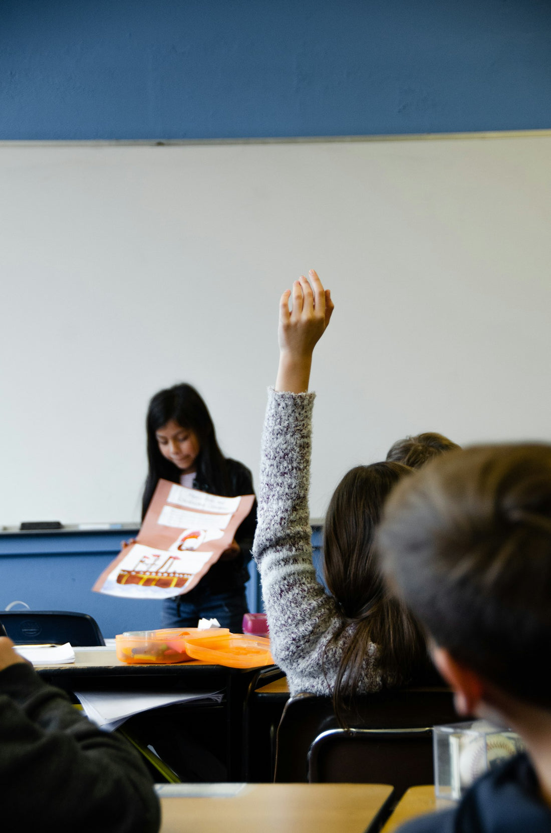 A young girl raising her hand to ask a question in a classroom