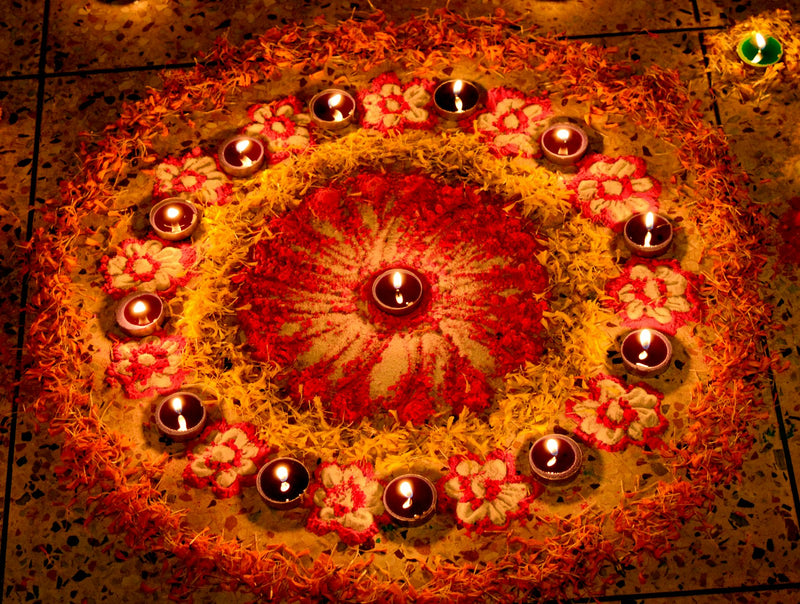 A circular arrangement of lit diyas on the floor for Diwali