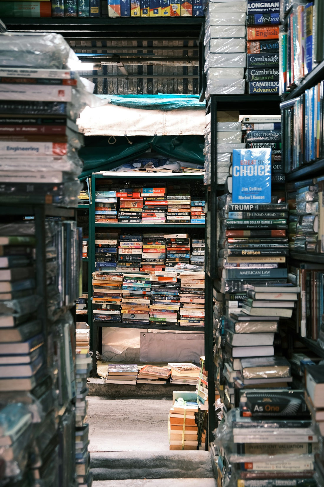 Densely packed bookstore shelves, rows of colorful book spines filling the frame from floor to ceiling.