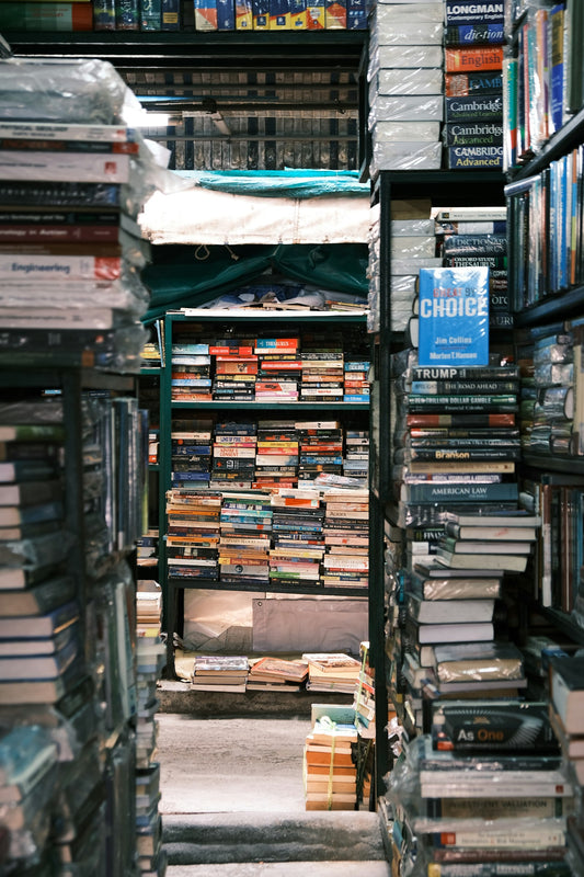 Densely packed bookstore shelves, rows of colorful book spines filling the frame from floor to ceiling.