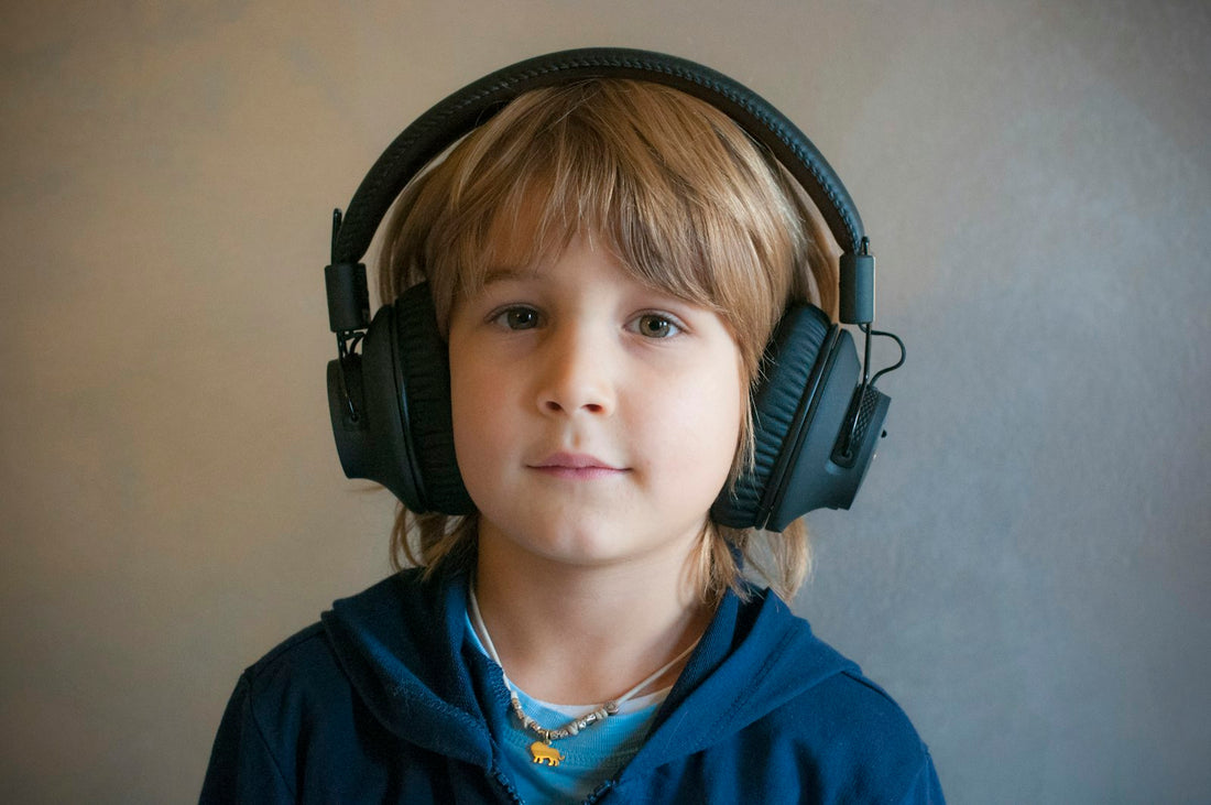 A young boy wearing large over-ear headphones, eyes closed, listening intently