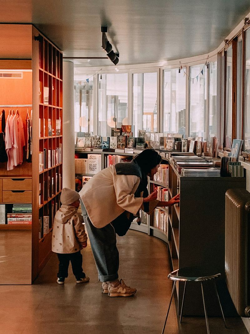 A woman and child browsing shelves of books together in a bookstore