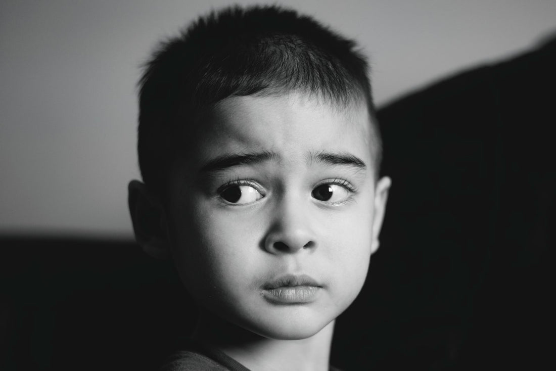 A young boy looks off to the side with wide, curious eyes.