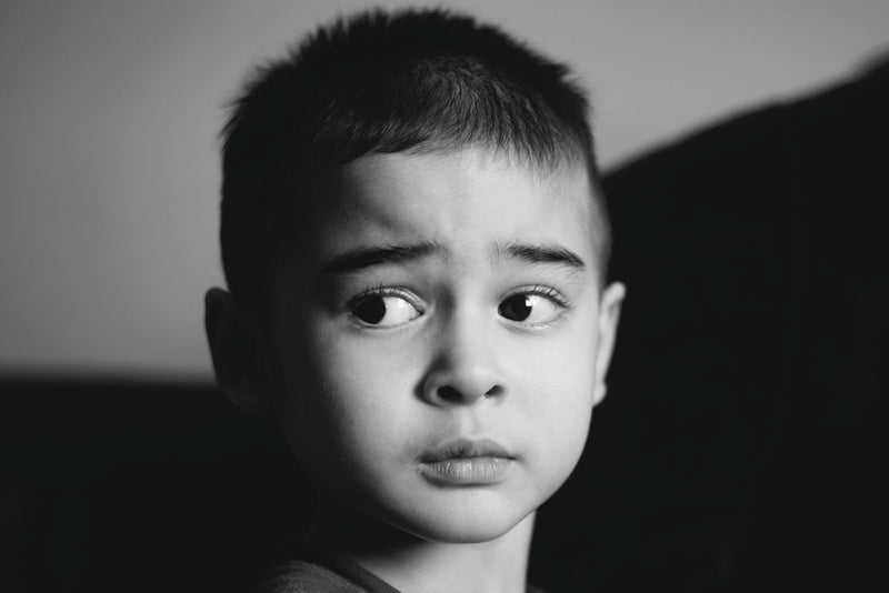 A young boy looks off to the side with wide, curious eyes.